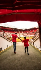 A man and boy in stadium tunnel looking out to pitch