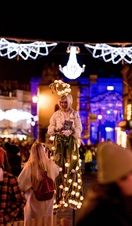 A street entertainer under Christmas lights along the high street in Bath