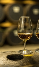 Two glasses of whisky standing on an oak barrel