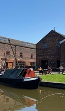 Exterior view of a canal and canalboat outside a Victorian workshop.