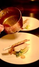Closeup of someone pouring sauce over a food dish