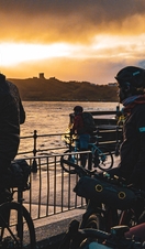 A group of cyclists taking a picture of the sunset on the coast