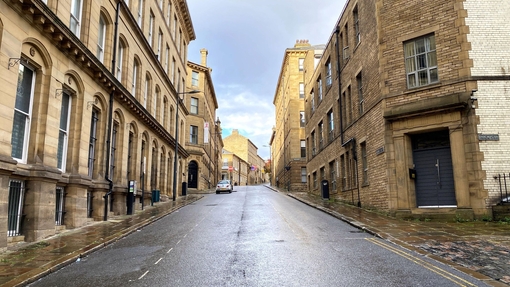 Looking up a deserted road, lined with Victorian stone buildings