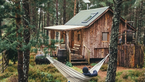 Person relaxing in hammock outside wood cabin