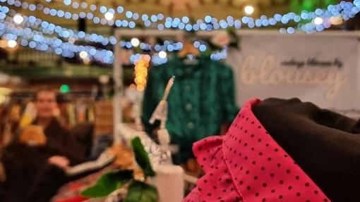 Close up of clothing on market stall at Victoria Baths with coloured lights in the background