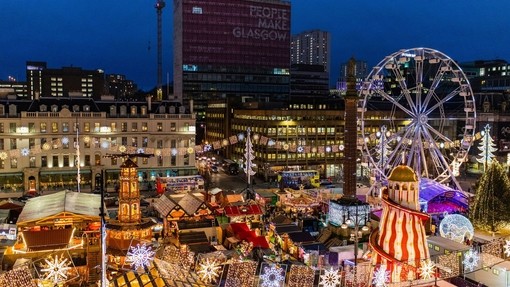 Christmas Market in a city lit up with festive lighting in the evening.