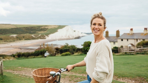 Lächelnde Frau auf dem Fahrrad mit weißen Klippen im Hintergrund