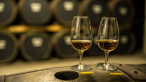 Zwei Gläser mit Whisky stehen auf einem Eichenfass