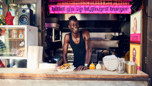 Smiling man working at food stall serving burgers