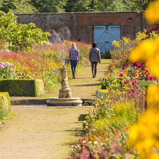 Two female friends walking through a formal garden