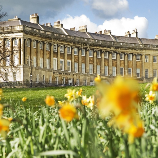 External view, through a field of blurred out daffodils in the foreground, of the Royal Crescent Hotel and Spa, Bath