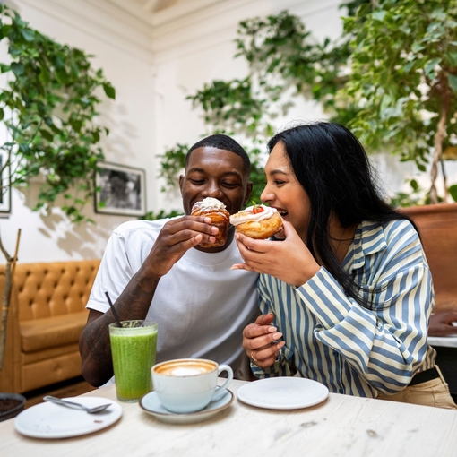 A man and a woman have cake and drinks in a cafe