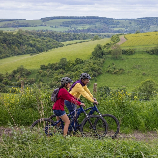 A man and a woman stand with bicycles wearing helmets