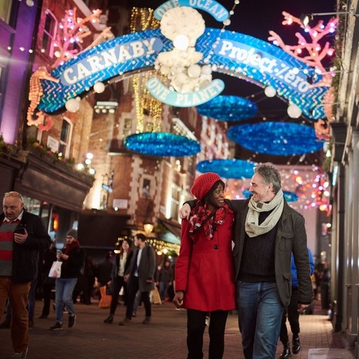 Couple walking down street under christmas lights