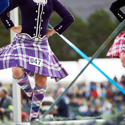 Three kilted girls Scottish dancing on stage