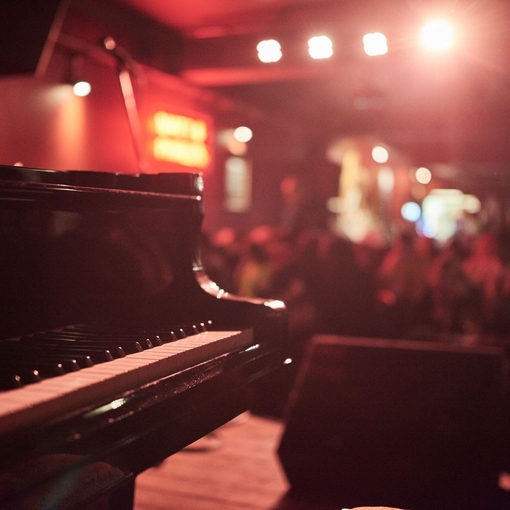 Pianist playing in a moodily lit bar. Red lighting