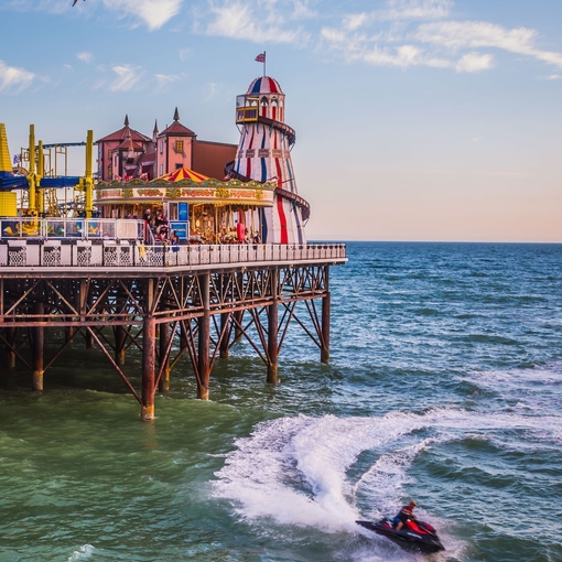 Jetski in sea below a seaside pier with a funfair