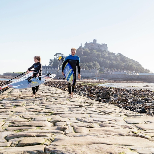 Windsurfer walking across the exposed causeway path of stone