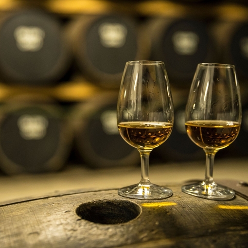 Two glasses of whisky standing on an oak barrel