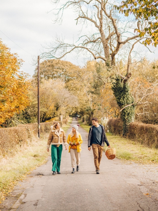 Two women and a man walking on a country lane in autumn