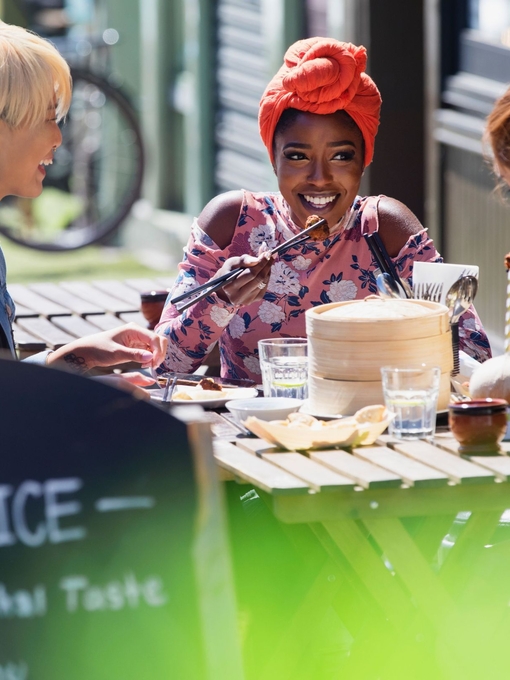 Three young women friends enjoying dim sum lunch at a sunny pavement cafe