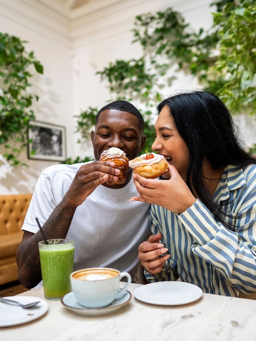 A man and a woman have cake and drinks in a cafe