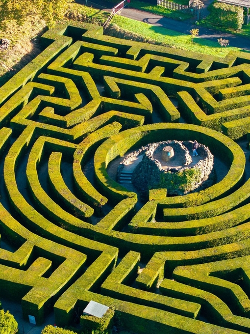 Aerial view of woman walking up the central tower of a hedge maze