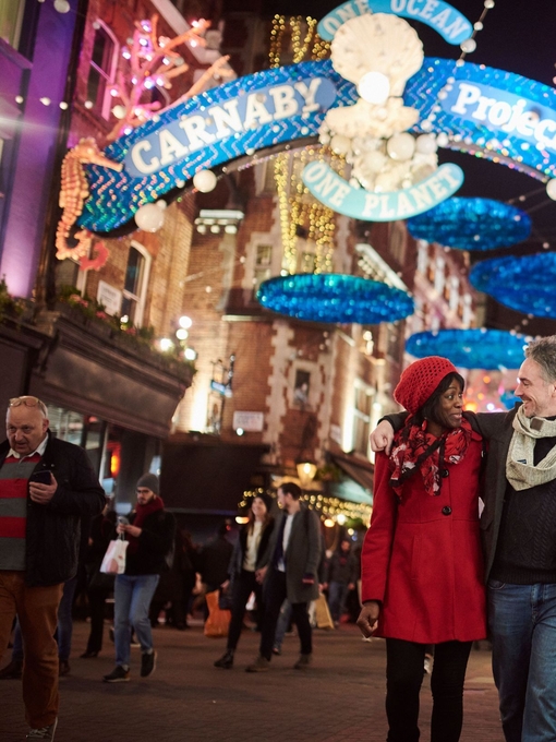 Ein Paar geht unter Weihnachtsbeleuchtung eine Straße entlang