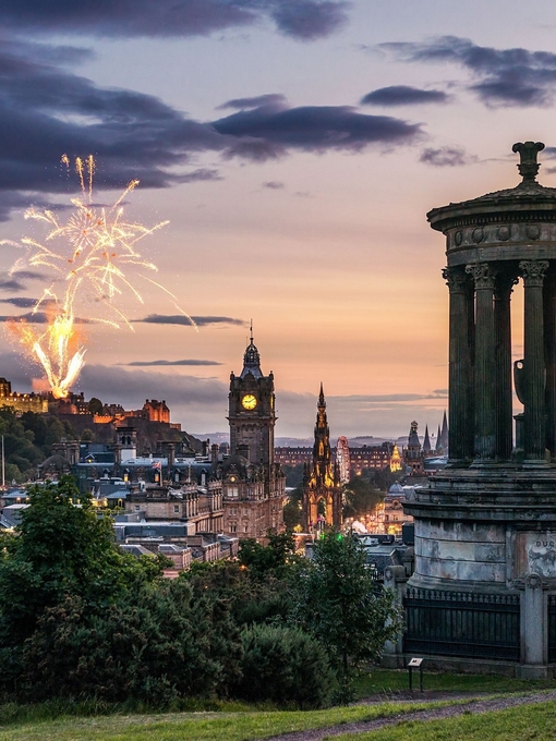 Fireworks at dusk in the sky over historic monument.