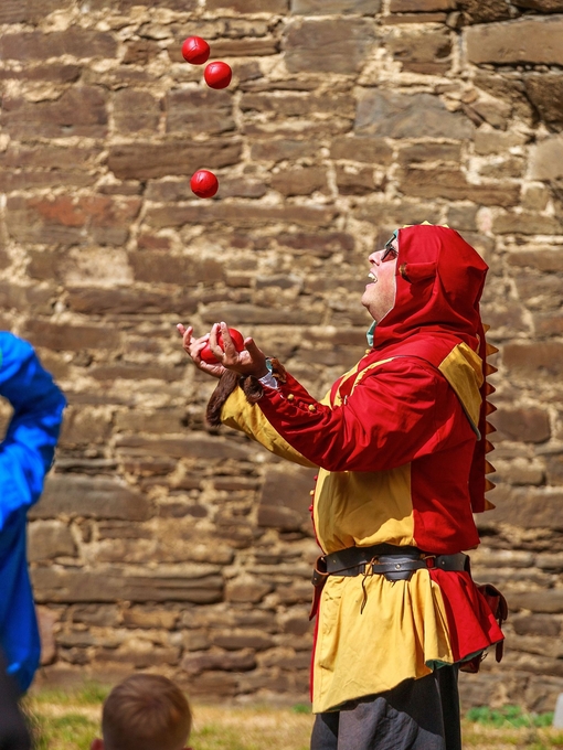 A juggler in costume juggling balls at Castell Coch in Wales
