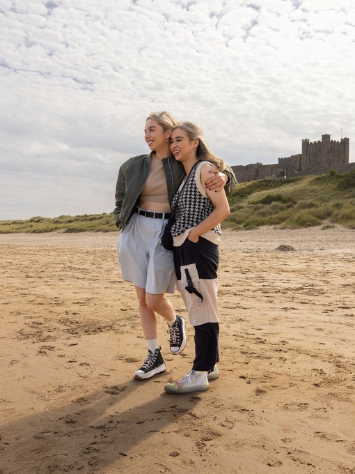 Two women hugging on the beach near a castle