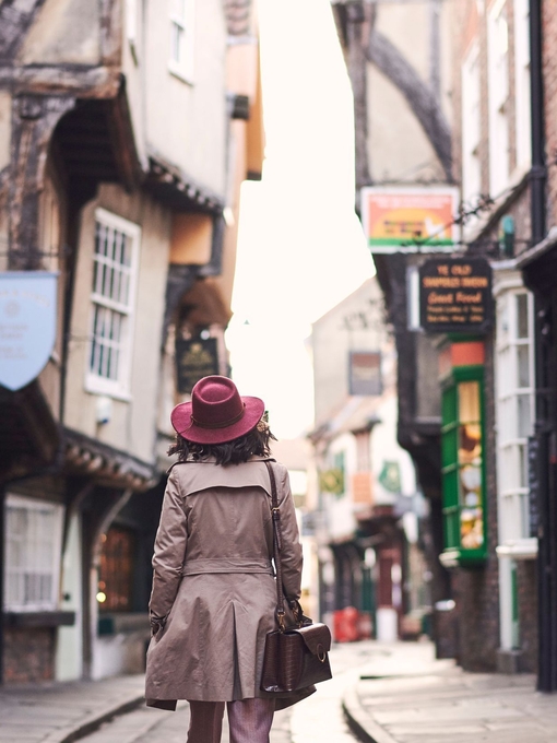 Woman wearing trench coat and pink hat walking
