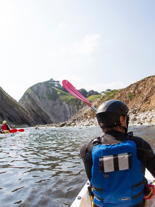 People kayaking along the shores of coastline