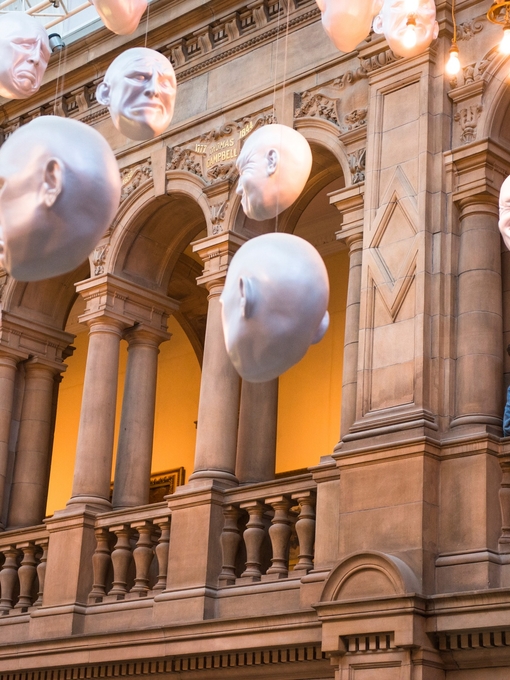 Two men looking at installation of suspended head sculptures