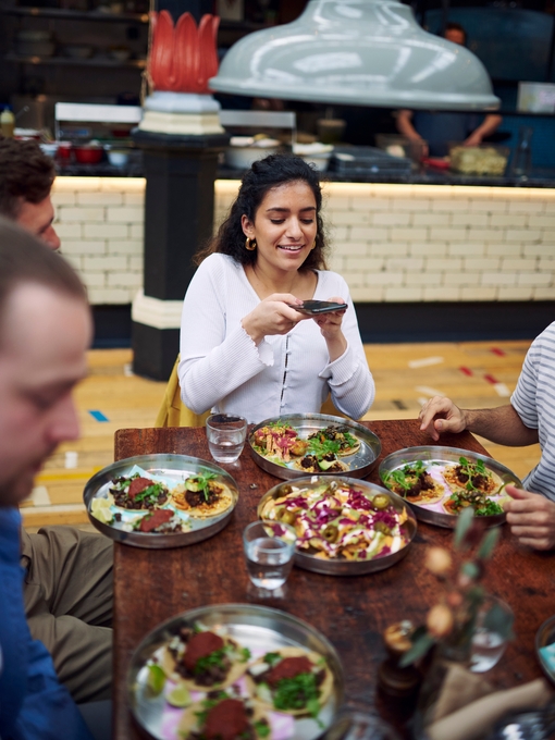 Girl taking a picture of her food at Mackie Mayor