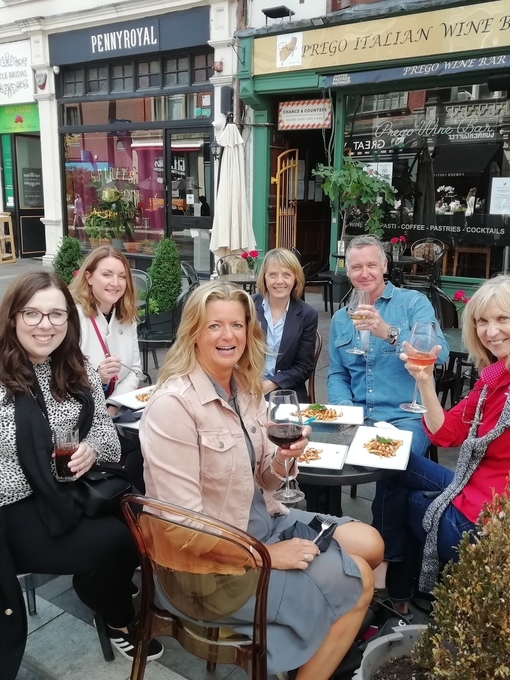 A group of people eating and drinking at an outside table at Cosmo, Cardiff
