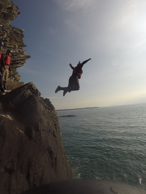 A group of people jumping from low cliffs into the sea near Snowdonia/Eryri National Park