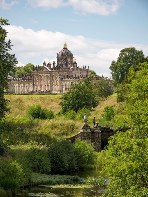 Large country house surrounded by trees with stream in the foreground