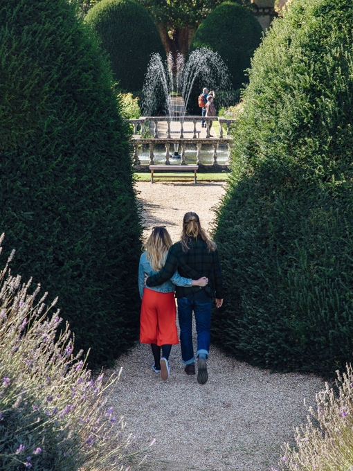 Male and female couple hugging in a garden near a fountain