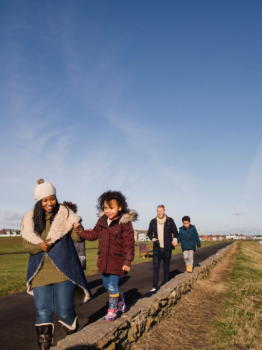 Family and friends walking along a coastal path in the winter sunshine