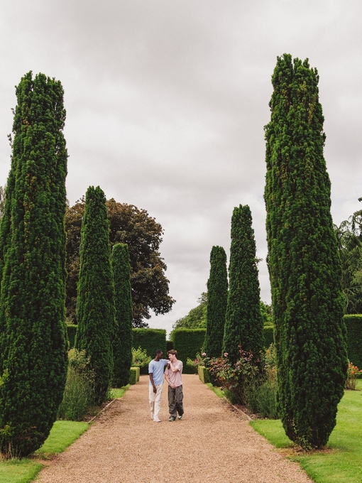 Two young men walk through ornate gardens