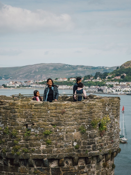 Family on top of a castle enjoying river views with boats docked and hills in the distance