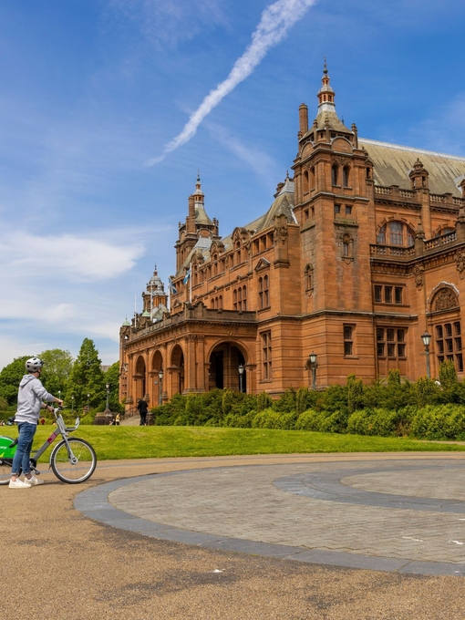 A cyclist parked out the front of an ornate Art Gallery and Museum.