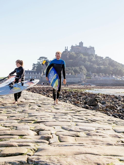 Windsurfer walking across the exposed causeway path of stone