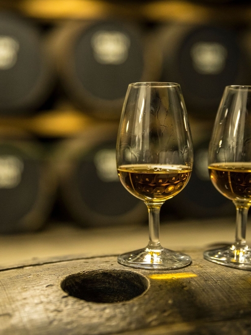 Two glasses of whisky standing on an oak barrel