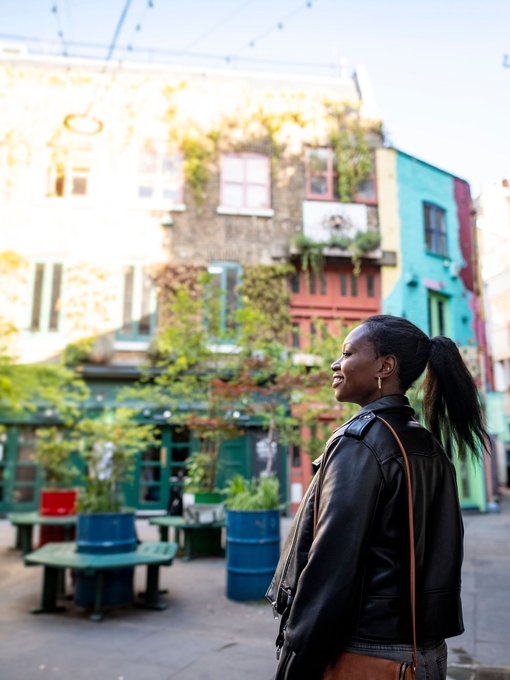 Female tourist exploring a London shopping courtyard with shops and outdoor seating.