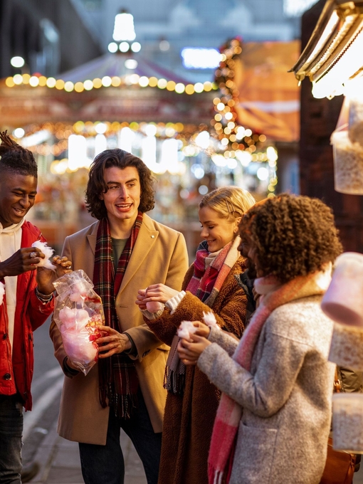 Group of young friends sharing a bag of cotton candy at the Christmas market