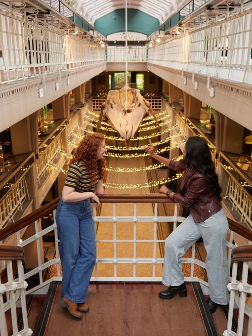 Deux femmes discutent et rient en visitant l'exposition sur la préhistoire dans un grand musée.