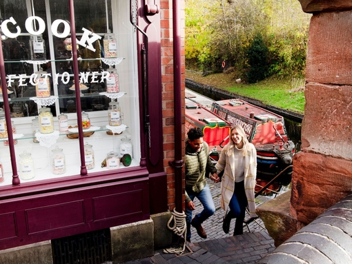 Couple walking up steps by the side of a sweet shop and canal