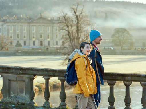 A young couple standing at the balustrade of a stone bridge
